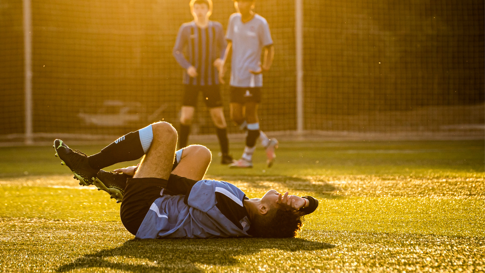 voetballer die met pijn op de grond ligt met enkelblessure en behandeld door chiropractor